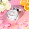 ANJALI MD Skincare Heavenly Moisturizing Cream Jar - Pictured next to some of its ingredients: Rose Petals, White Rose, Oranges - On a pink gradient background