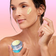 Woman holding Age Rewind Face Serum and applying a small smear to her face